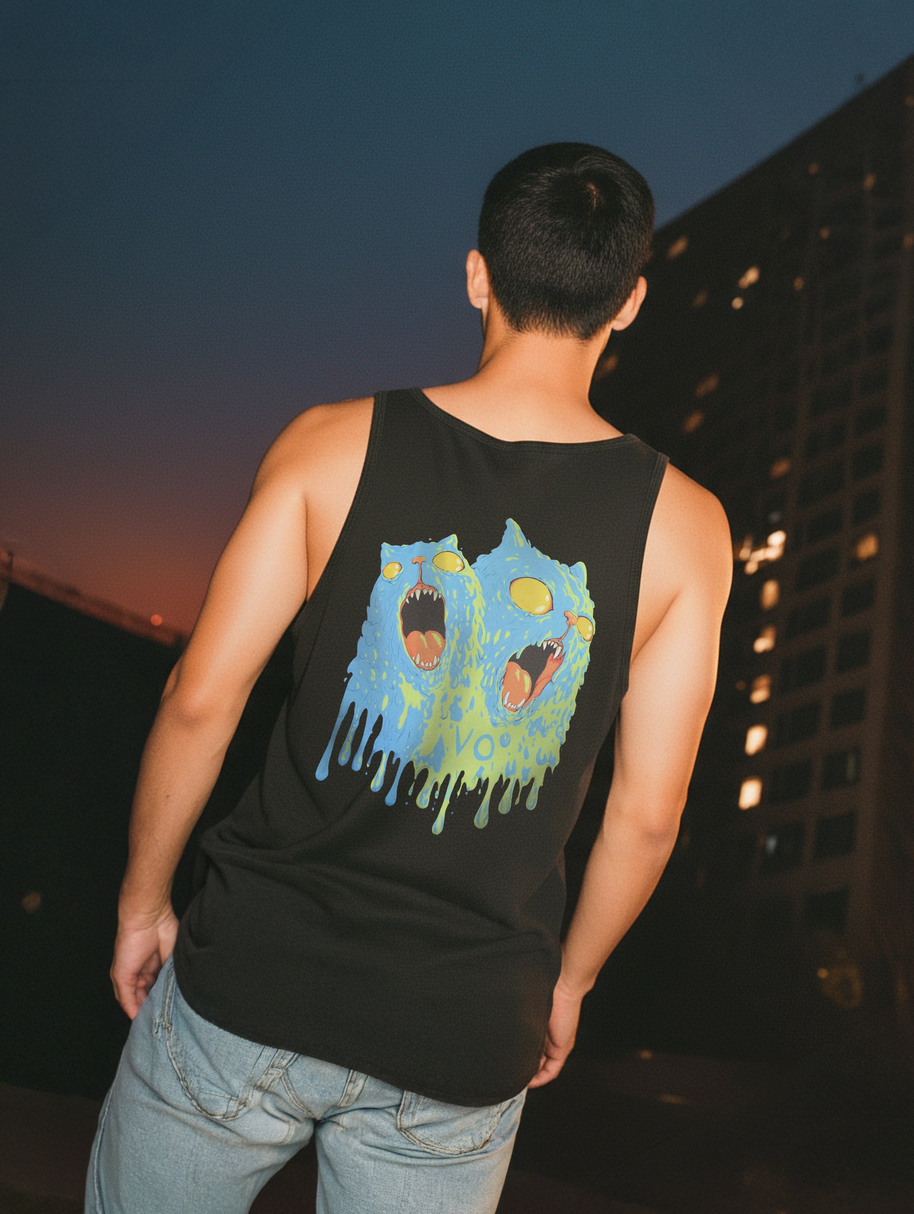 Person wearing a black tank top with a colorful graphic design outdoors at dusk.