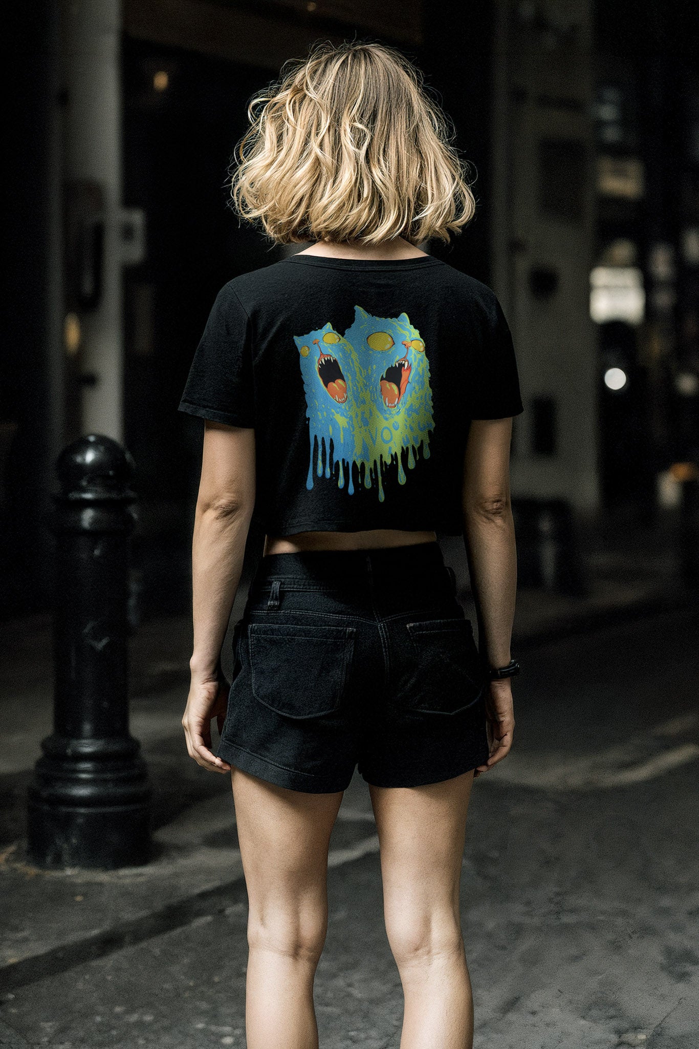Person wearing a black t-shirt with a colorful graphic on the back, standing on a street.